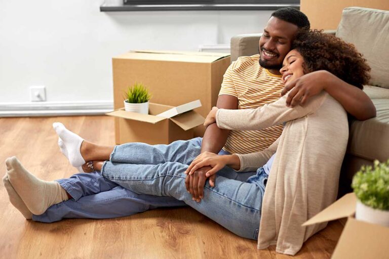 First-time homebuyers reviewing house plans and documents at a kitchen table.