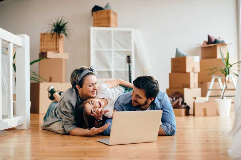 Buyers review a Closing Disclosure and settlement papers at a table beside house keys and a calculator.